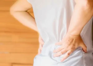 Person holding their lower back with both hands, indicating back pain or discomfort.