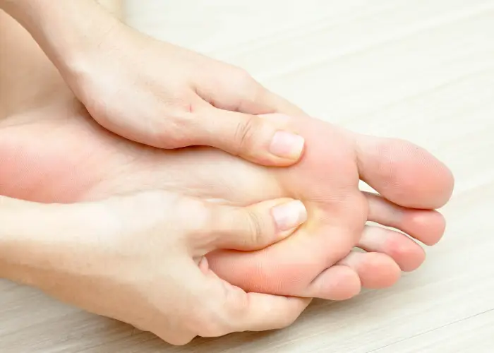 Hands massaging the sole of a foot, indicating foot pain, tension, or plantar fascia discomfort.