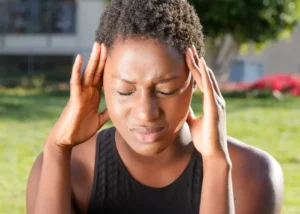 Person holding their head with both hands, eyes closed, showing signs of headache or stress..