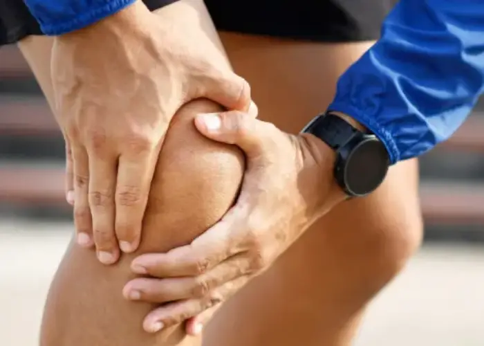 commercial-plumbing Person holding their knee with both hands, showing knee pain during physical activity