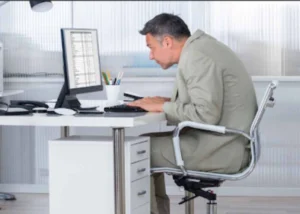 Person leaning forward toward a computer screen with poor posture, illustrating the need for posture correction.