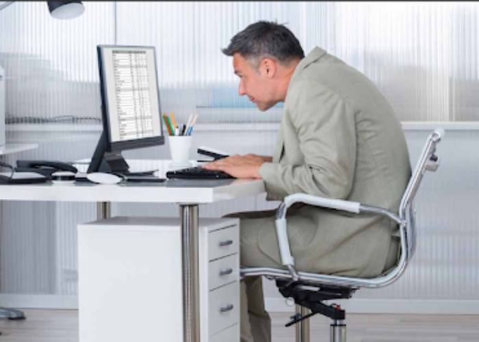 Person leaning forward toward a computer screen with poor posture, illustrating the need for posture correction.