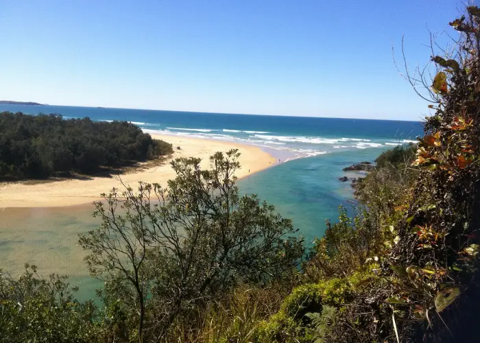 Aerial coastal view of Boambee with estuary, sandy beach and surrounding greenery.