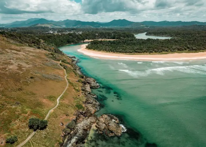 Aerial coastal view near Boambee East with sandy beach, turquoise water and surrounding greenery.