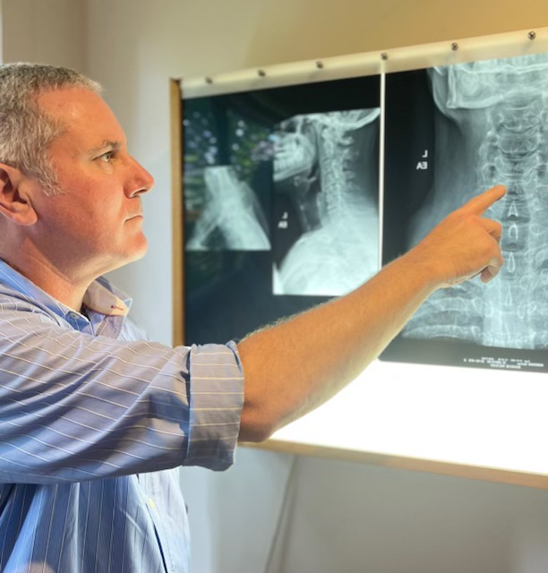 gas-pipeline Chiropractor reviewing cervical spine X‑rays during a patient examination at Harris Chiropractic.