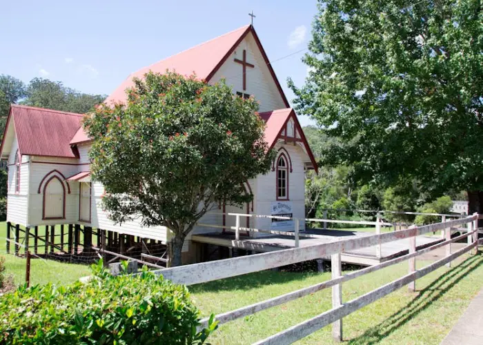 Small rural church in Coramba with cream walls, red roof and surrounding greenery.