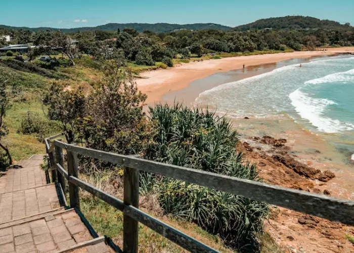 Coastal view of Emerald Beach with sandy shoreline, rocky edges and surrounding greenery