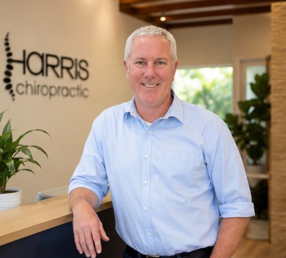 Chiropractor standing at the Harris Chiropractic reception desk in Coffs Harbour, welcoming patients into the clinic.