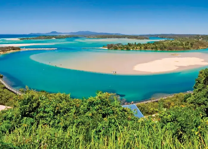 Aerial view of Nambucca Heads with turquoise estuary, sandbars and surrounding greenery.