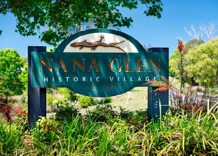 Nana Glen historic village sign surrounded by lush greenery and sunlight.