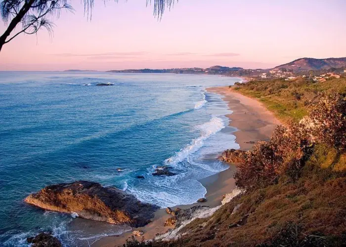 Coastal view of Sapphire Beach with waves, rocky headlands and soft sunrise colours.