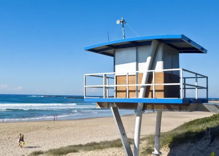 Lifeguard tower overlooking Sawtell Beach with waves and clear blue sky.