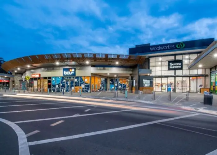 Evening view of Toormina Gardens shopping centre with Woolworths and bcu storefronts.