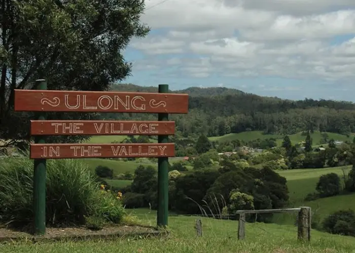 Ulong village sign with rolling green hills, scattered trees and rural landscape.