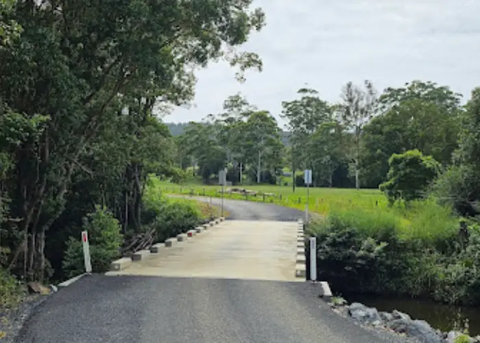 Small rural bridge in Upper Bucca crossing a creek with surrounding trees and open fields.