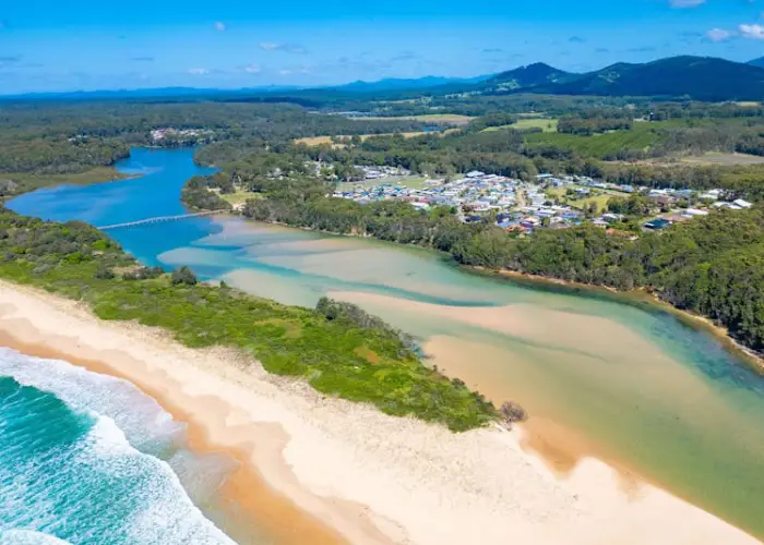 Aerial view of Valla Beach showing sandy coastline, river mouth and surrounding greenery.